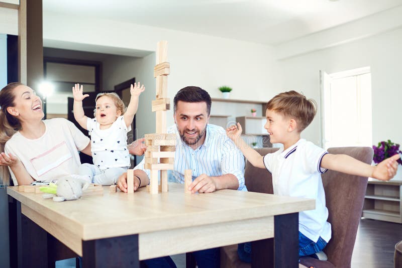 Une famille joue des jeux de société se reposant à une table à l'intérieur