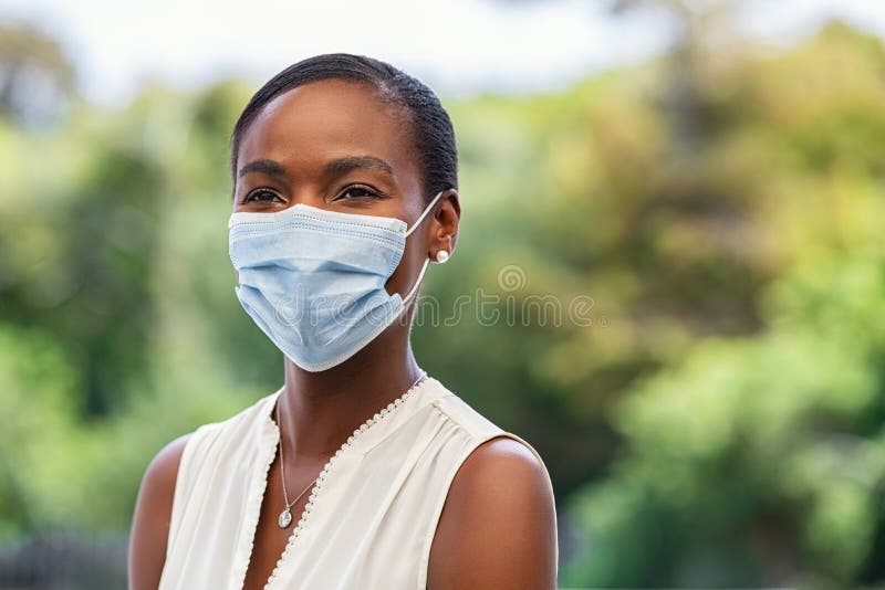 Mature african american woman wearing covid-19 protective face mask and looking away. Beautiful black woman in park wearing surgical mask for safety against coronavirus with copy space. Mid adult happy female portrait outdoor during pandemic, looking for positive future. Mature african american woman wearing covid-19 protective face mask and looking away. Beautiful black woman in park wearing surgical mask for safety against coronavirus with copy space. Mid adult happy female portrait outdoor during pandemic, looking for positive future