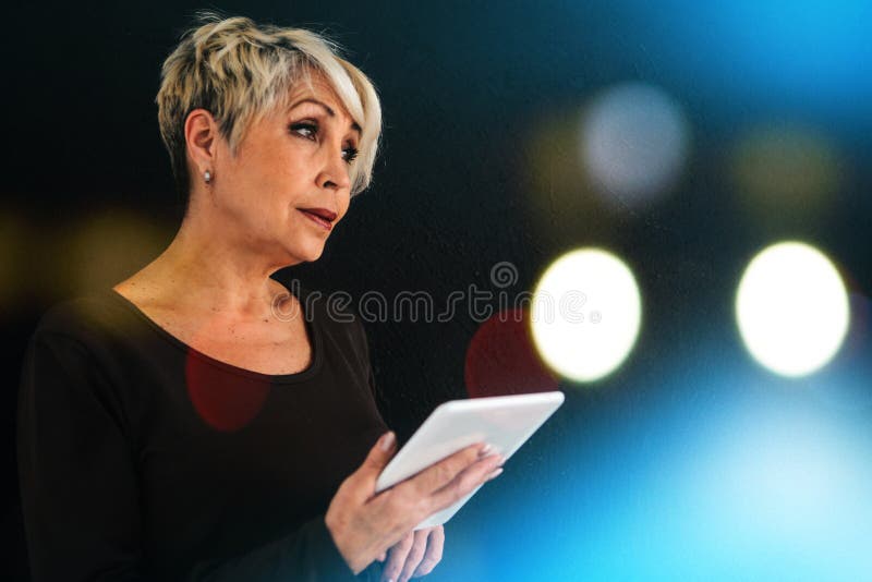Une femme agée moderne positive réussie tient un comprimé dans des ses mains et l'emploie La génération plus ancienne et moderne image libre de droits Une femme agée moderne positive réussie tient un comprimé dans des ses mains et l'emploie La génération plus ancienne et moderne image libre de droits