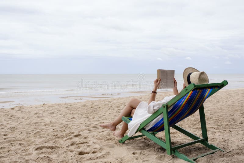 Une femme allongée et lisant un livre sur le transat se sentant détendue photo stock
