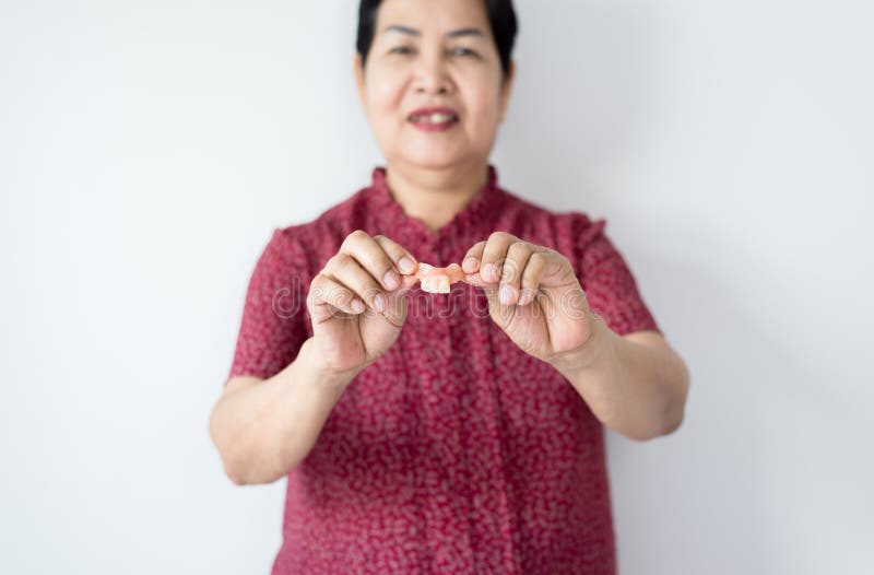 Une femme asiatique âgée tient des dents dans les mains, prothèse dentaire, fausses dents, fermer les yeux photos stock Une femme asiatique âgée tient des dents dans les mains, prothèse dentaire, fausses dents, fermer les yeux photos stock