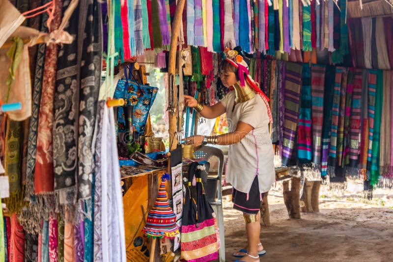 Une femme avec un long cou et des anneaux sur elle prépare un compteur pour la vente des écharpes en soie photo stock Une femme avec un long cou et des anneaux sur elle prépare un compteur pour la vente des écharpes en soie photo stock