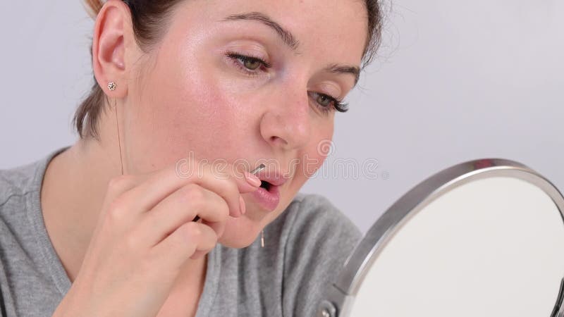 Une femme caucasienne regarde dans le miroir et enlève la moustache elle-même avec l'aide de pince. hirsutisme. banque de vidéos