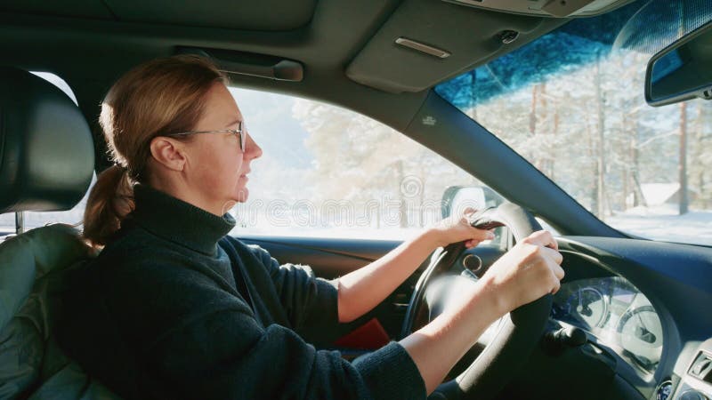 Une femme conduisant habilement une voiture à travers un magnifique paysage hivernal scénique qui captive les sens banque de vidéos