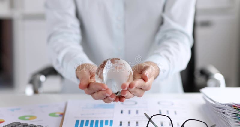 Une femme d'affaires tient un globe de verre sur son lieu de travail banque de vidéos