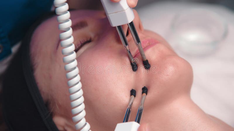 Une femme d'âge moyen subit des procédures de rajeunissement facial électrothérapeutique dans un bureau de cosmétologistes.