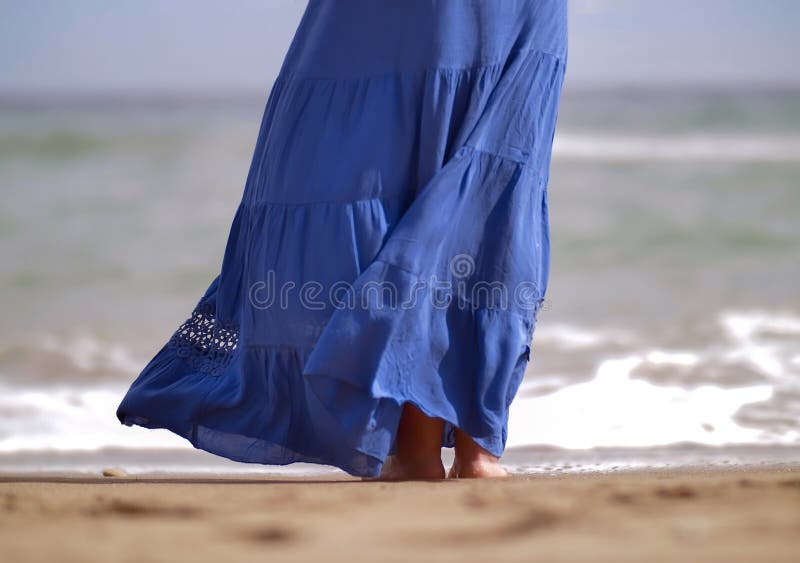 Une femme dans une longue jupe bleue se tient sur la plage photographie stock libre de droits Une femme dans une longue jupe bleue se tient sur la plage photographie stock libre de droits