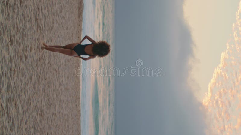 Une femme détendue profiter de la promenade en bord de mer sable près des vagues de l'océan vue verticale arrière banque de vidéos