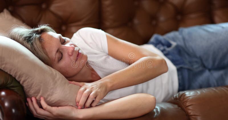 Une femme détendue repose sur le canapé en cuir doux coussin support corps banque de vidéos