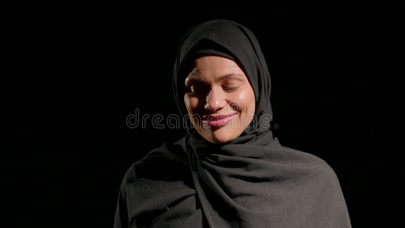 Une femme en hijab noir sourit doucement pour montrer sa chaleur et sa confiance. Sent un cadre rose est lumineux et contraste som banque de vidéos