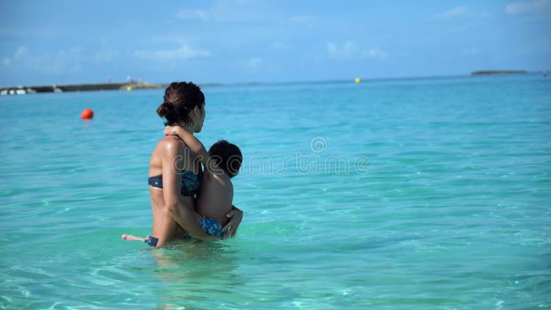 Une femme et un enfant sont dans l'océan avec la femme qui tient l'enfant banque de vidéos