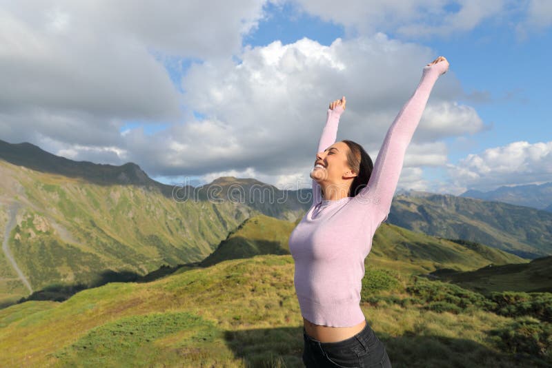 Une femme excitée levant les bras dans la montagne célébrant