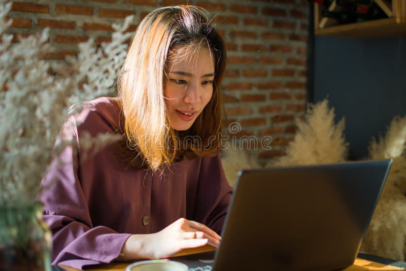Une femme fait des emplettes sur l'Internet tout en mettant le peu de sourire sur son visage photographie stock Une femme fait des emplettes sur l'Internet tout en mettant le peu de sourire sur son visage photographie stock