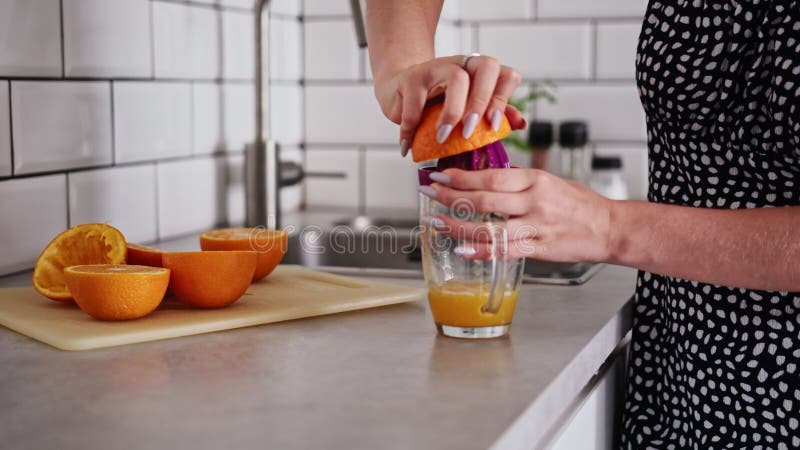 Une femme fait du jus d'orange à la maison dans la cuisine clips vidéos