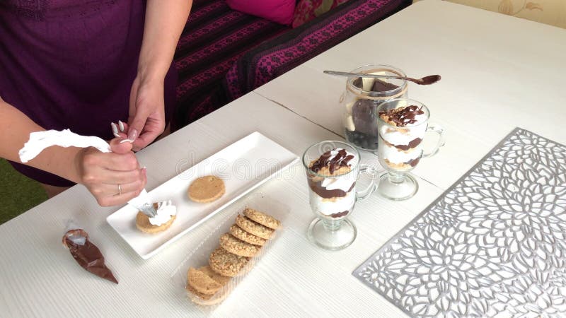 Une femme fait un sandwich de biscuits chocolat et crème. place la crème sur les cookies banque de vidéos