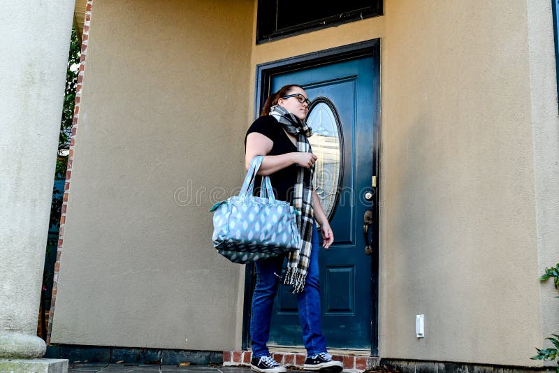 Une femme ferme à clef son entrée principale pendant qu'elle part à la maison avec un sac marin plus d'un bras image libre de droits Une femme ferme à clef son entrée principale pendant qu'elle part à la maison avec un sac marin plus d'un bras image libre de droits