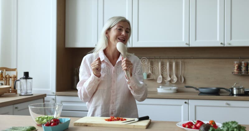 Une femme heureuse dansant chante en cuisine clips vidéos