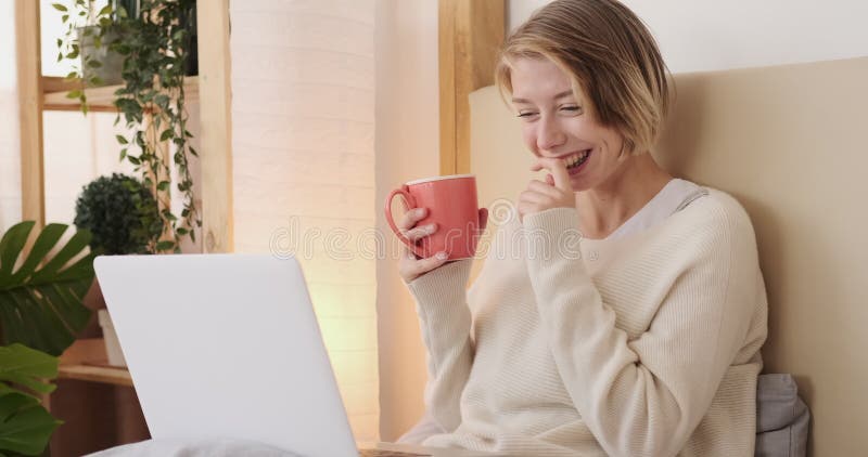 Une femme heureuse en train de discuter en vidéo avec un ordinateur portable dans son lit banque de vidéos