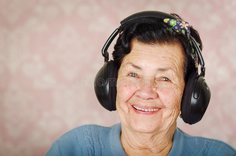 Une femme hispanique adorable plus âgée utilisant le chandail bleu, arc de modèle de fleur sur la tête devant le papier peint ros photo libre de droits Une femme hispanique adorable plus âgée utilisant le chandail bleu, arc de modèle de fleur sur la tête devant le papier peint ros photo libre de droits