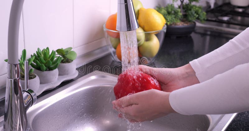 Une femme lave un poivron rouge frais dans la cuisine clips vidéos