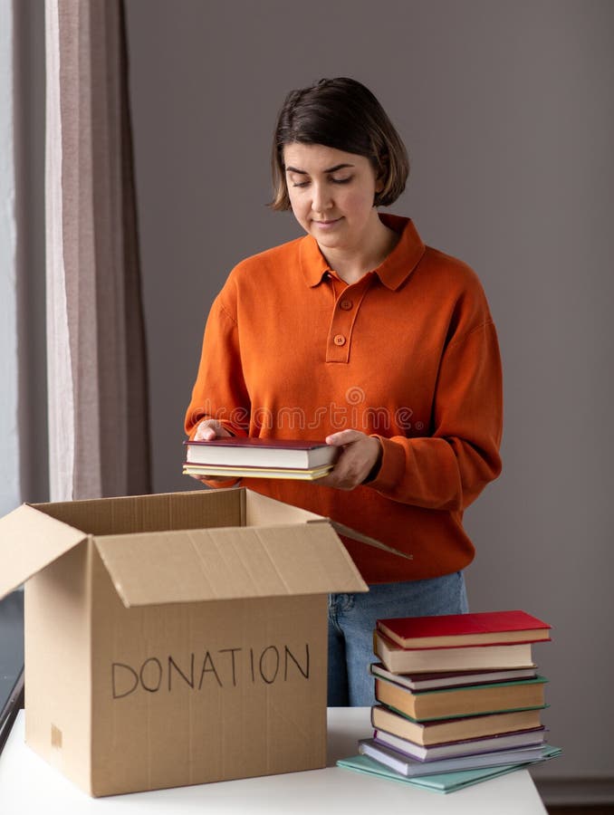 Une femme met des livres dans une boîte en carton pour un don photo stock