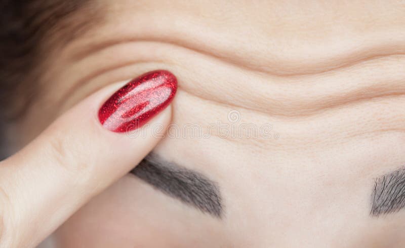 Une femme montre les rides profondes sur son front Procédé de vieillissement image stock Une femme montre les rides profondes sur son front Procédé de vieillissement image stock