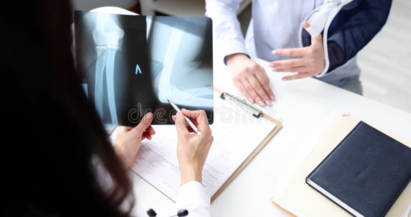 Une femme médecin analyse l'image du coude Xray avec un patient à l'hôpital banque de vidéos