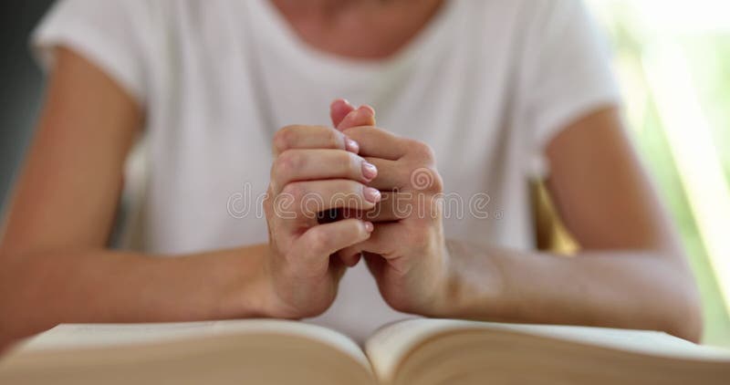 Une femme nerveuse prie en jouant les mains sur la Bible ouverte chez elle banque de vidéos