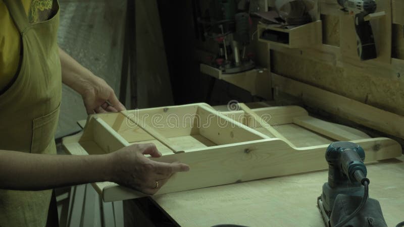 Une femme peint une partie en bois d'un produit en bois avec une brosse. idée d'entreprise pour un atelier à domicile