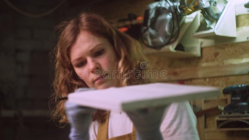 Une femme peint une partie en bois d'un produit en bois avec une brosse. idée d'entreprise pour un atelier à domicile