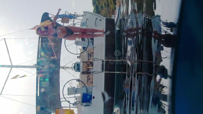 Une femme plonge du yacht à l'eau. Vue sur et sous la surface de l'eau. Vidéo verticale banque de vidéos
