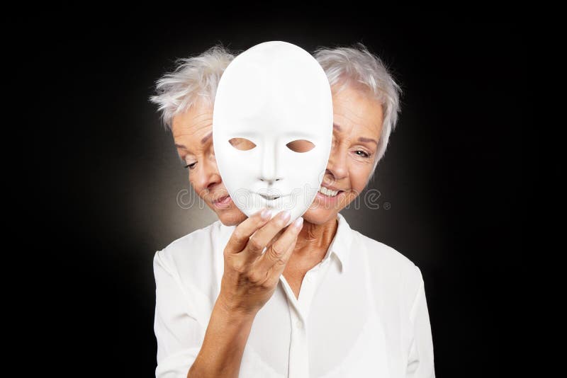 Older woman hiding happy and sad face behind mask, concept for manic depression or bipolar or dramedy comedy drama. Older woman hiding happy and sad face behind mask, concept for manic depression or bipolar or dramedy comedy drama