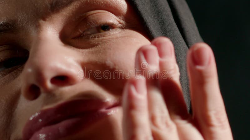 Une femme portant le hijab lui applique doucement le visage tout en souriant. Chambre bien éclairée créant une atmosphère chaleure banque de vidéos