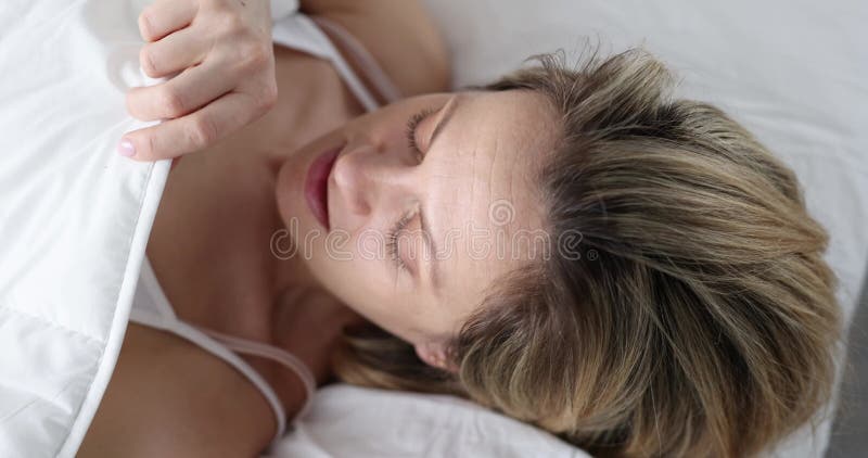 Une femme regarde sous le choc sous les couvertures pendant qu'elle est allongée au lit banque de vidéos