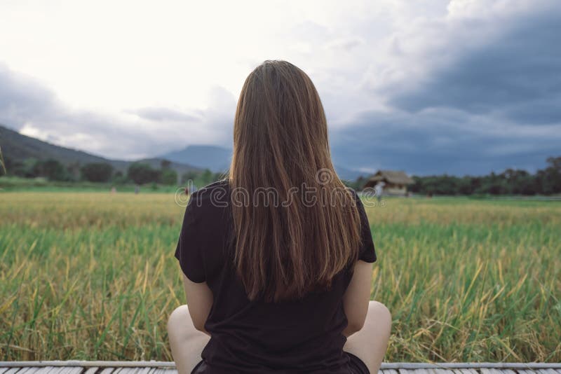 Une femme reposant et regardant un beau gisement de riz en avant avec se sentir décontracté image libre de droits
