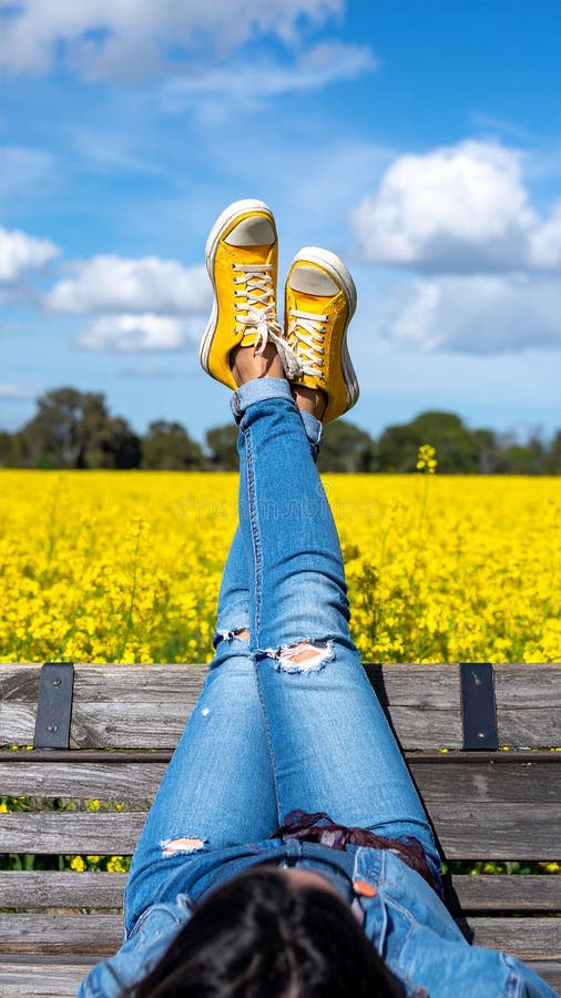 Une femme se reposant avec ses jambes soutenue sur un banc au milieu d'un champ de jaune illustration de vecteur