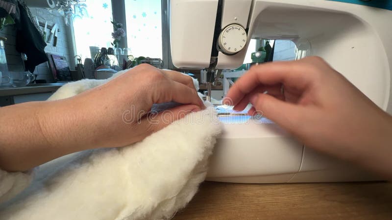 Une femme travaille dans une machine à coudre. elle coud un lit d'animal de compagnie en tissu de fourrure. elle coud le fond du l banque de vidéos