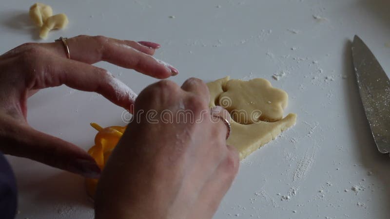 Une femme utilise des biscuits pour faire des biscuits dans de la pâte roulée banque de vidéos