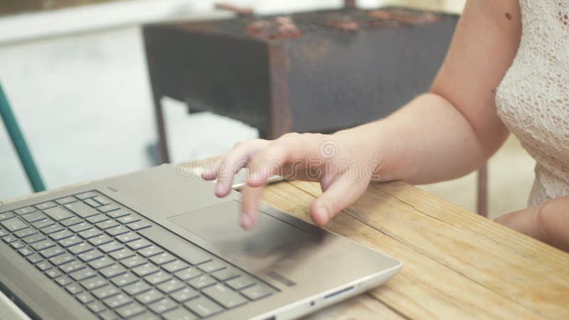 Une femme utilise un ordinateur portable dans la rue. extérieur une table en bois dans la cour de la maison. communication de natu banque de vidéos