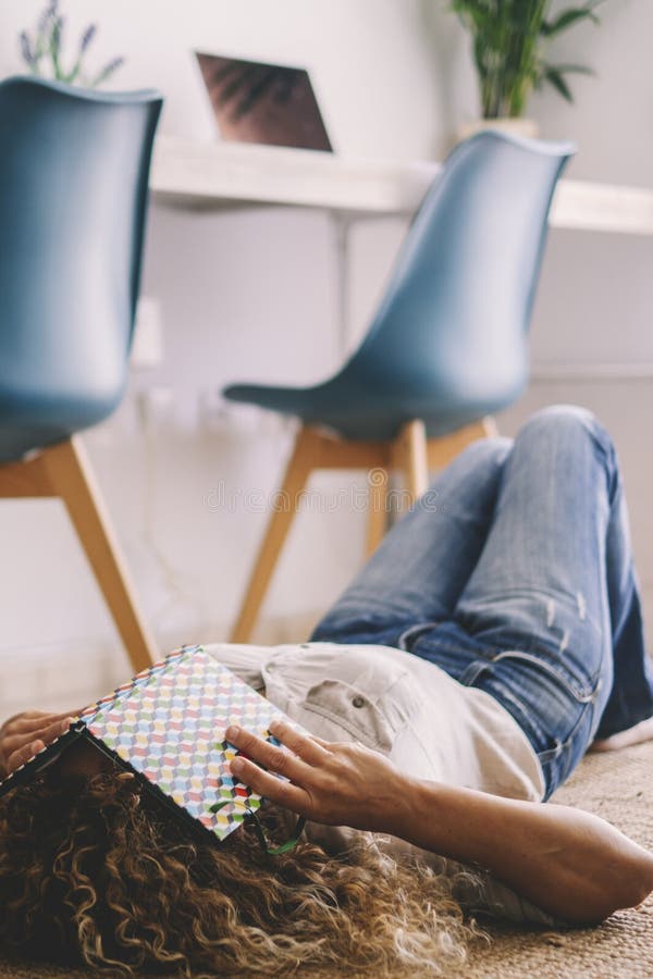 Une femme à la maison s'est allongée sur le tapis recouvrant son visage d'un livre. concept d'éducation et d'âge moyen étudiant. f photos libres de droits