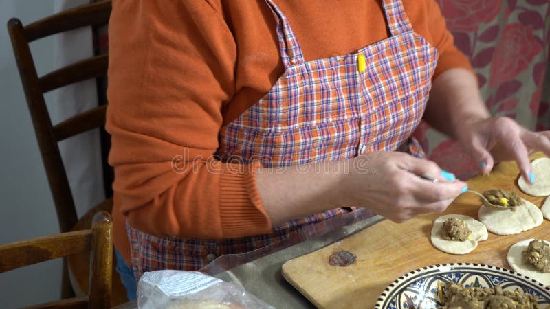 Une femme âgée fait des tartes avec de la viande. pâte maison. Grand-mère fait la cuisine. banque de vidéos