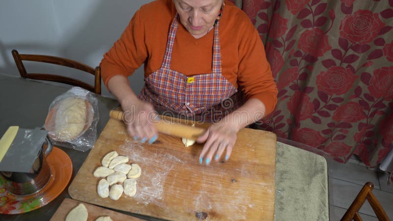 Une femme âgée fait des tartes avec de la viande. pâte maison. Les mains de grand-mère cuisinent la nourriture. clips vidéos