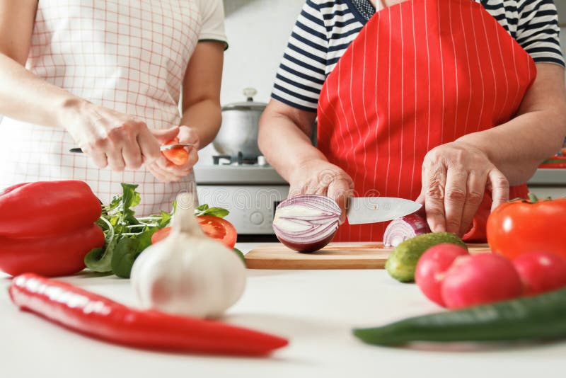 Une fille adulte et une mère âgée cuisinent ensemble à la maison dans la cuisine Aliments sains et frais images stock Une fille adulte et une mère âgée cuisinent ensemble à la maison dans la cuisine Aliments sains et frais images stock