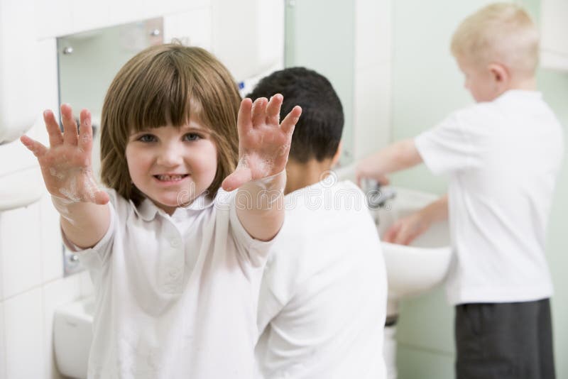 Une fille affichant ses mains dans une salle de bains d'école photo libre de droits Une fille affichant ses mains dans une salle de bains d'école photo libre de droits