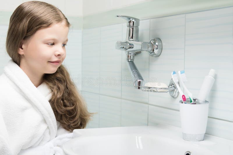 Une fille dans un peignoir est venue à la salle de bains pour se brosser les dents image stock Une fille dans un peignoir est venue à la salle de bains pour se brosser les dents image stock