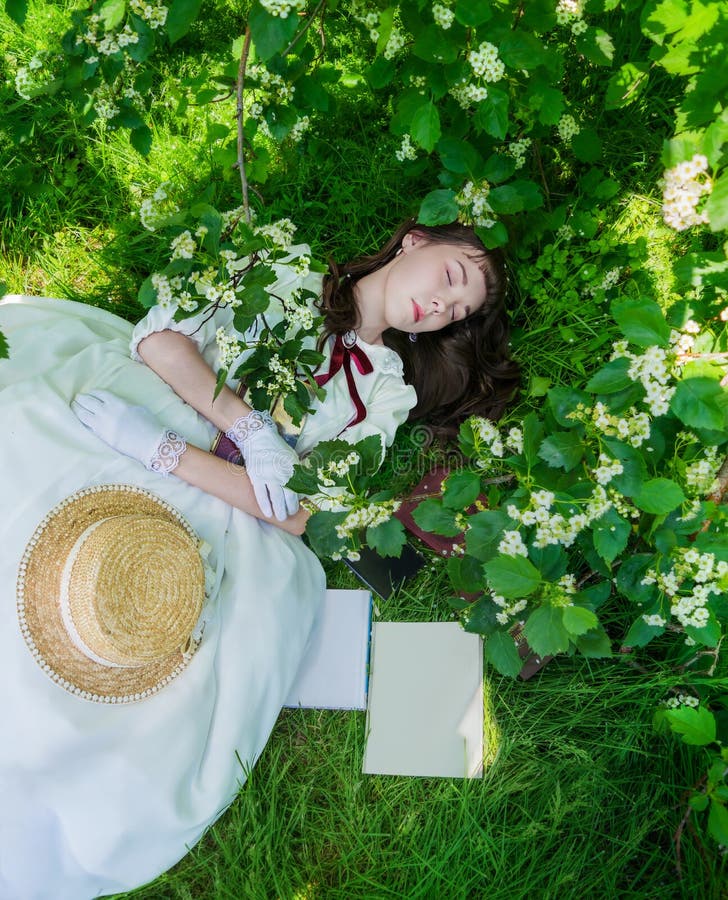 Une fille en robe blanche s'est endormie sous un arbre avec un livre photographie stock