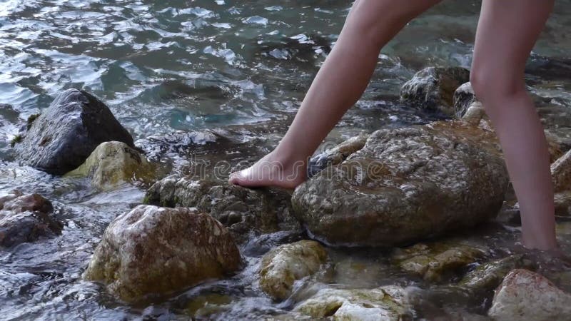 Une fille entre dans l'eau sur une plage de pierre