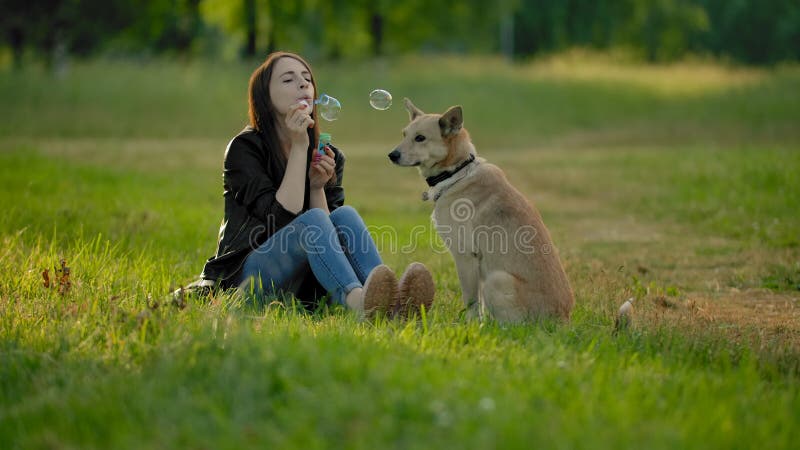 Une fille fait exploser des bulles de savon dans le parc à son chien