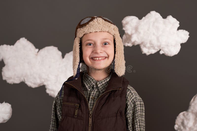 Une fille habillée dans une veste rétro et casque de style avec des verres et des rêves de devenir pilote de nuages cotonneux gris photographie stock
