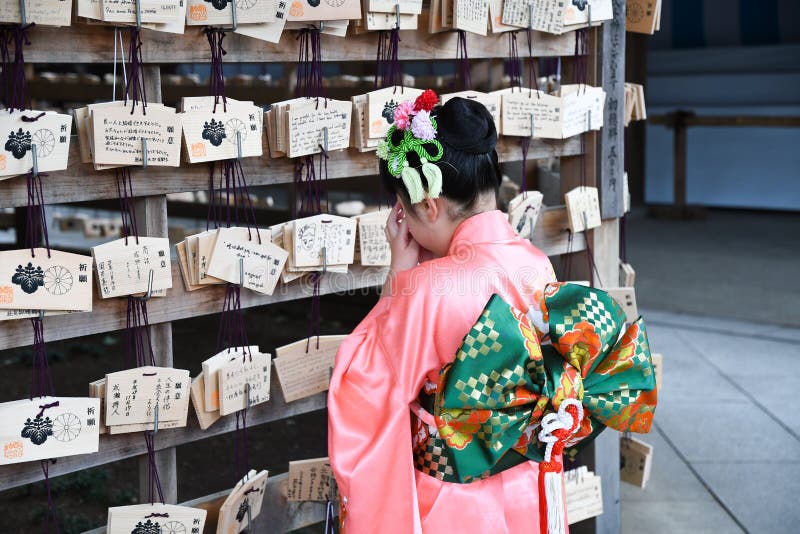 Une fille japonaise priant devant les panneaux de prières image libre de droits Une fille japonaise priant devant les panneaux de prières image libre de droits